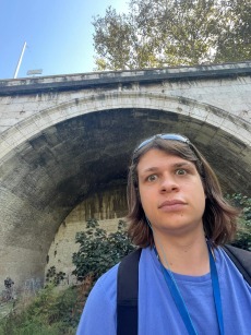 A young man proudly stands in front of the Cloaca Maxima