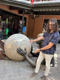 Justice standing in front of a statue of a person pushing a rock